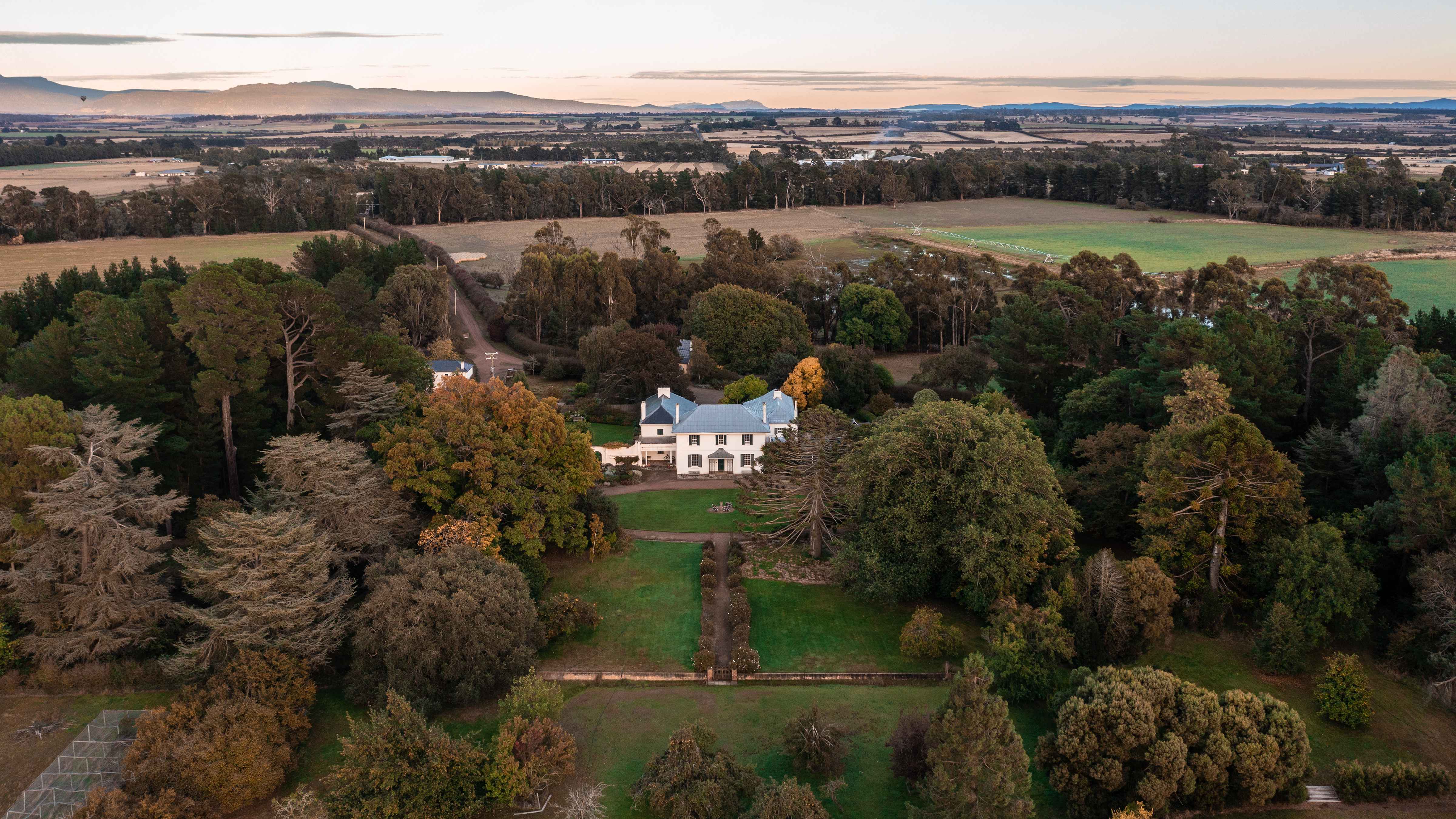 Aerial image of Brickendon homestead surrounded by the heritage gardens and parkland. The photo background extends over neighbouring farming properties to the Western Tiers. Photo: Kate von Stieglitz / Tourism Australia.