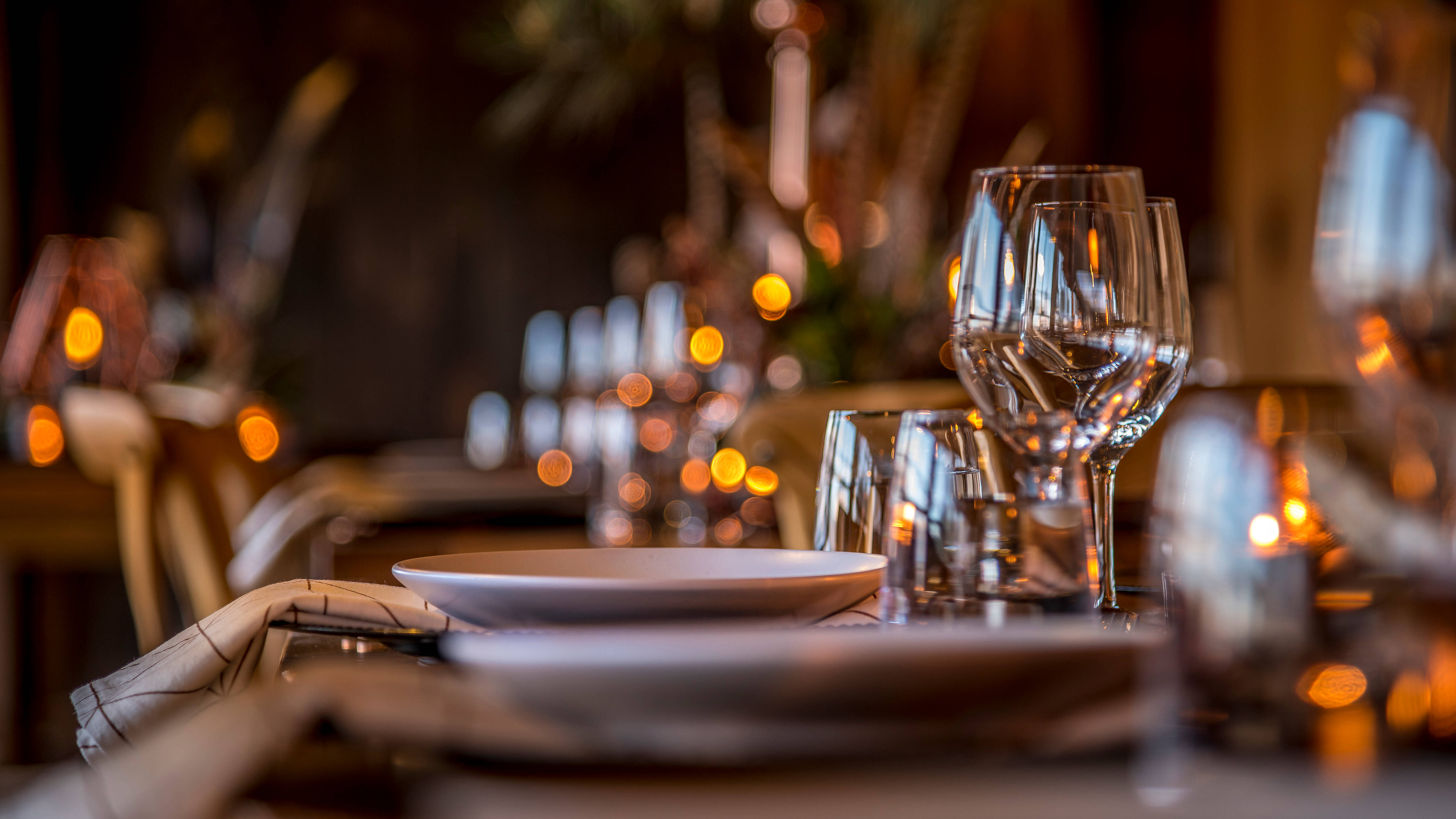 A close up image of wine glasses and crockery set on tables. Photo: Rob Burnett.