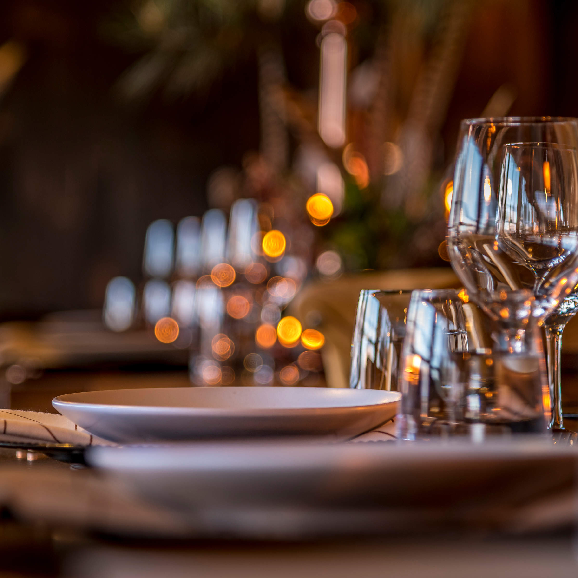 A close up image of wine glasses and crockery set on tables. Photo: Rob Burnett.