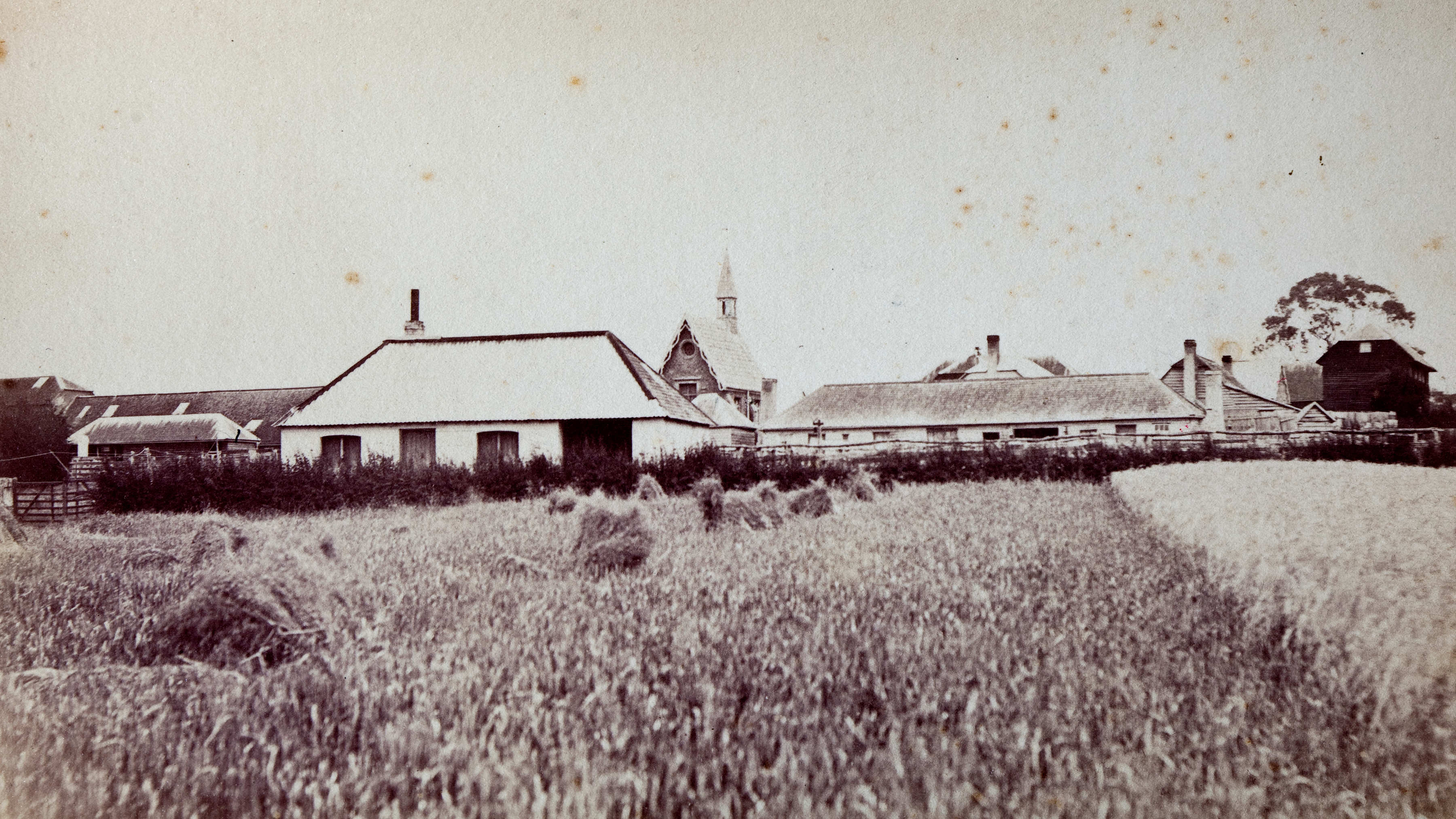 Blacksmith’s shop in the foreground with the convict quarters, carpenter’s hut, sawyer’s hut and chapel visible behind, c1880.